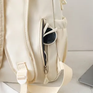 Detail of hidden zipper pocket on cream backpack with sunglasses storage inside