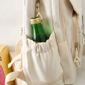 Detail view of cream nylon backpack side pocket with elastic opening and silver zipper