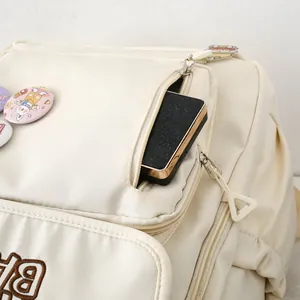 Detail of off-white backpack featuring side zipper pocket and cute cartoon bunny badge
