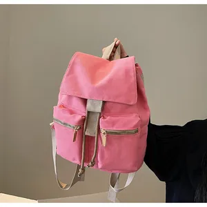 Detalle de mochila de lona rosa con cierre de cordón y dos bolsillos frontales con cremallera