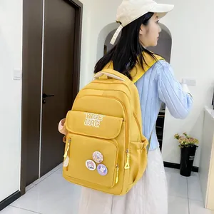 Close-up of yellow nylon backpack featuring cute rabbit badges and multiple compartments