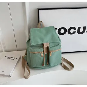 Detalle de mochila de lona verde con cierre de cordón y cremalleras de metal dorado
