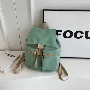 Detalle de la mochila de lona verde menta con cierre de cordón y cremalleras doradas frontales