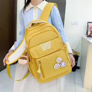 Model wearing a bright yellow multi-pocket backpack with cute cartoon pins and pendants