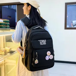 Close-up of black waterproof nylon backpack featuring cute cartoon pins and charms