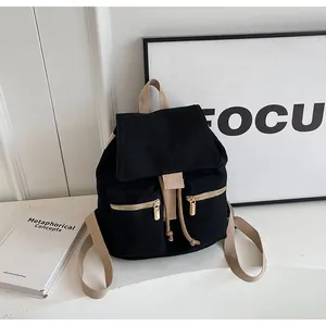 Detalle de mochila de lona negra con correas caqui y elegantes cremalleras doradas