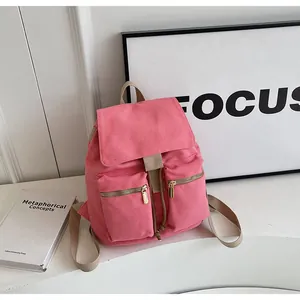 Mochila de lona rosa con cremalleras doradas y dos bolsillos frontales exteriores