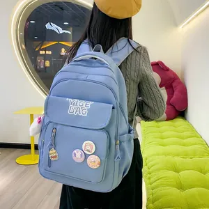 Detail of light blue waterproof nylon backpack with cute badges and hamburger pendant charm