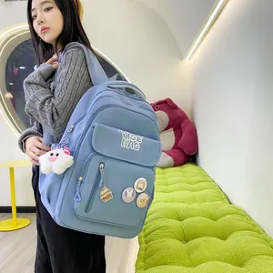 Detail of light blue nylon backpack with multiple pockets and cute decorative charms