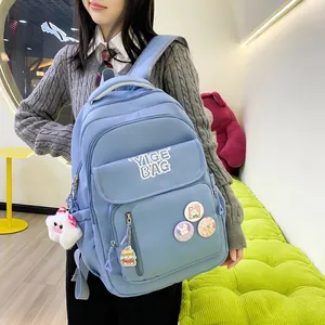 Detail of light blue student backpack with YIGE BAG logo and cute cartoon charms
