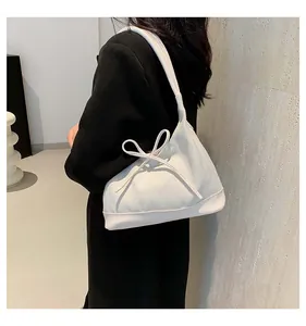 Close-up of white canvas tote bag with leather trim and delicate bow detail