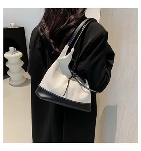 Detail of canvas tote bag with black leather bow accent and contrast trim design