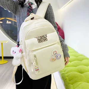Detail of cream white canvas backpack featuring multiple zip pockets and cute plush charm