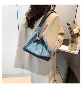 Blue denim and black leather shoulder bag with bow detail on a blazer-clad model