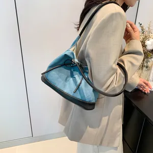 Minimalist blue canvas and black leather patchwork tote bag with a decorative bow