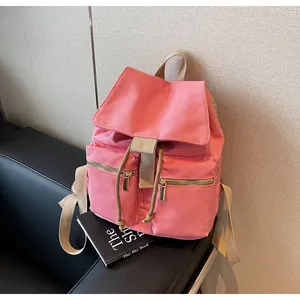 Detalle de mochila de lona rosa con cremalleras doradas y cierre de cordón ajustable