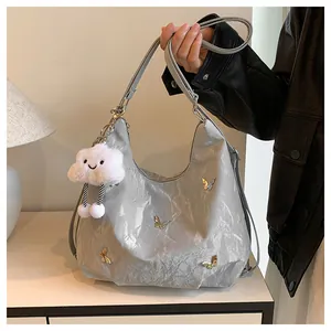Détail du sac cabas argenté avec papillons métalliques et texture plissée chic