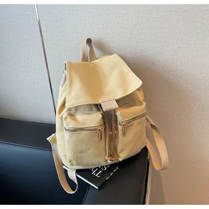 Vista detallada de mochila de lona beige con cierre de cordón y cremalleras metálicas