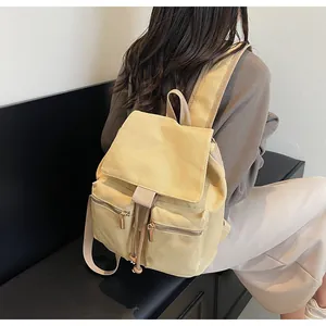 Detalle de una mochila saco de lona amarilla con cordón y bolsillos con cremallera metálica