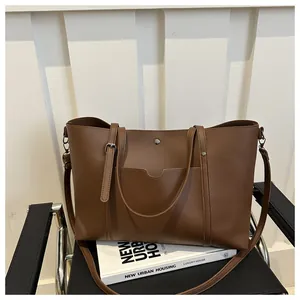 Macro detail of brown leather tote bag with unique pocket and metal magnetic buckle