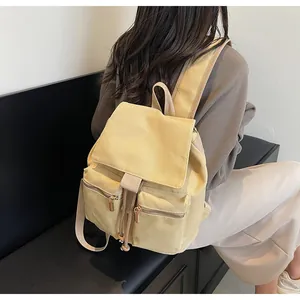 Vista trasera detallada de una mochila de lona beige con cordón y dos bolsillos frontales
