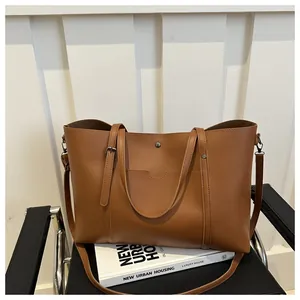 Close-up of brown leather tote bag with front pocket design and dual handles