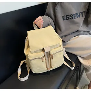 Detalle de mochila de lona beige con dos bolsillos delanteros con cremallera y cordón ajustable