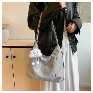 Gros plan sur le sac argenté avec papillon, texture métallisée et charme nuage en peluche