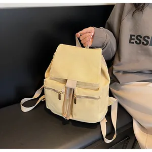 Detalle de mochila de lona amarillo claro con dos bolsillos frontales con cremallera y cordón