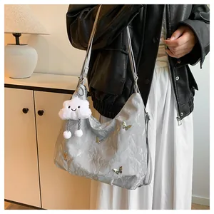 Détail du sac demi-lune argenté avec papillon doré et pendentif en forme de petit nuage