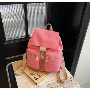 Vista detallada de una mochila de lona rosa con cremalleras doradas sobre mármol
