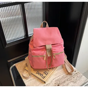 Detalle de mochila de lona rosa con cierre de cordón y herrajes metálicos dorados