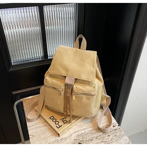 Detalle de mochila de lona amarillo claro con dos bolsillos frontales y correas ajustables
