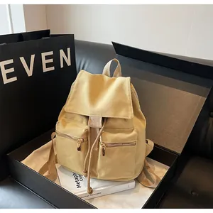 Detalle de mochila de lona amarilla con cordón y bolsillos frontales con cremallera