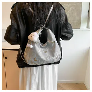 Détail du sac hobo argenté avec breloques papillons et pendentif nuage en peluche
