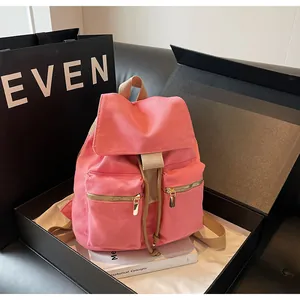 Detalle de mochila de lona rosa con cremalleras doradas y cierre de cordón ajustable