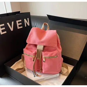 Detalle de mochila de lona rosa con cremalleras doradas frontales y cordón ajustable