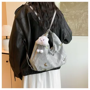 Détail du sac hobo argenté avec breloques papillon et pendentif en forme de nuage doux
