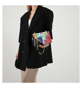Model wearing a colorful geometric patchwork chain shoulder bag with black blazer