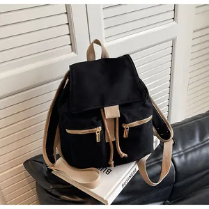 Vista detallada de mochila de lona con correas en contraste y cremalleras sobre libros blancos