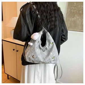 Sac fourre-tout gris argenté avec papillons métalliques et peluche porté à l'épaule