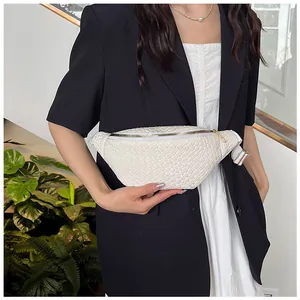 Primo piano di una borsa a tracolla bianca intrecciata con un cinturino largo su una modella
