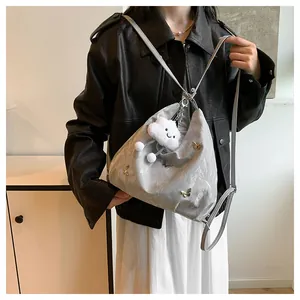 Détails du sac bandoulière argenté plissé avec papillon doré et breloque peluche