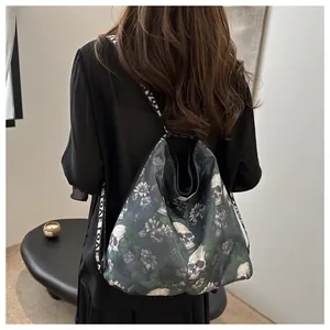 Detail of a black nylon crossbody bag featuring a skull flower print and LOVE straps