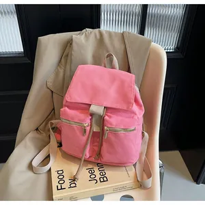 Detalle de mochila tipo saco en lona rosa con cremalleras doradas y cordón beige