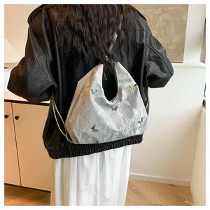 Détails du sac hobo argenté métallisé avec ornements papillons 3D et texture plissée