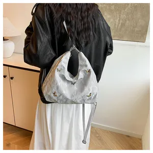 Sac hobo plissé argenté avec détails papillon métalliques et bandoulière longue