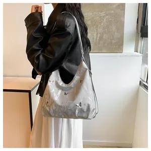 Détail du sac hobo argenté avec texture plissée Y2K et ornements de papillons métalliques