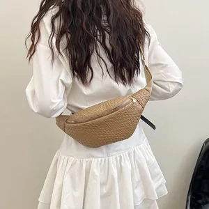 Borsa a tracolla alla moda con trama intrecciata e spallina larga indossata da un modello