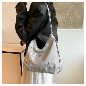 Détail du sac cabas argenté avec breloques papillon et texture plissée élégante